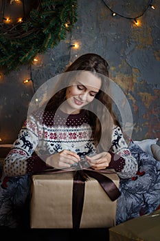 Smiling young girl with presents and gift boxes under the Christmas tree