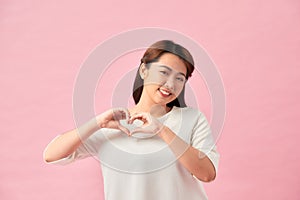 Smiling young girl showing heart with two hands, love sign