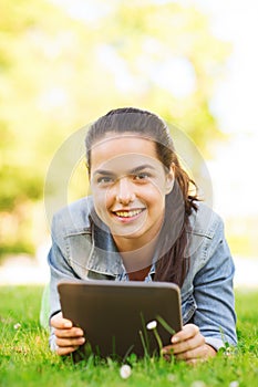 Smiling young girl tablet pc lying on grass