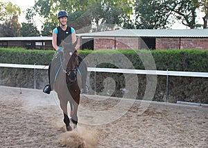 Smiling young girl trains horseback riding