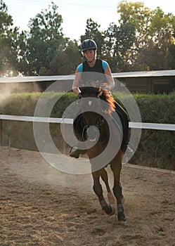 Smiling young girl trains horseback riding