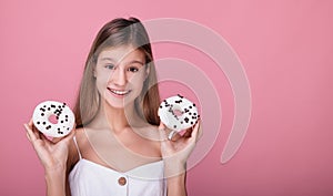 Smiling young girl in a white dress with donuts in white glaze