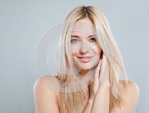 Smiling young good-looking female model with long colored hair and healthy skin portrait. Blonde woman looking at camera on gray