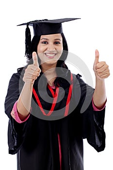 Smiling young graduation student making thumbsup gesture