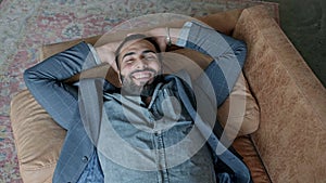 Smiling Young Guy Of Oriental Nationality Lies Down On The Sofa.