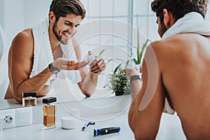 Smiling young guy preparing to shave his beard