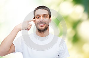 Smiling young handsome man pointing to eyes