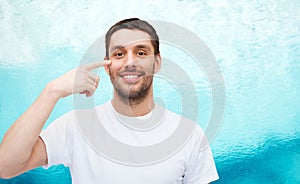 Smiling young handsome man pointing to eyes