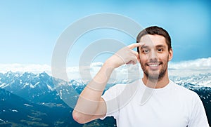 Smiling young handsome man pointing to forehead