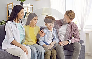 Smiling young happy family sitting on the sofa at home spending weekend together