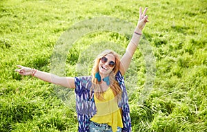 Smiling young hippie woman dancing on green field