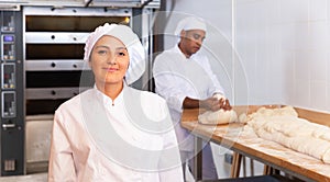 Smiling young hispanic female baker in bakery