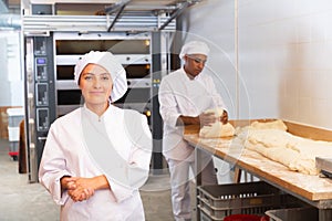 Smiling young hispanic female baker in bakery