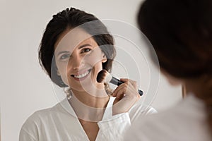 Smiling young hispanic woman doing makeup at home.