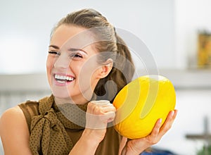 Smiling young housewife checking ripeness of melon