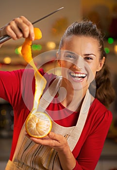 Smiling young housewife removing orange peel