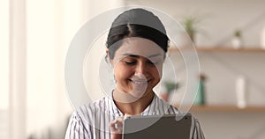 Smiling young indian ethnicity woman using touchscreen digital computer tablet.