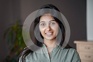 Smiling young indian lady looking at camera at home, headshot portrait.