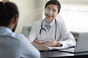 Smiling young Indian woman doctor consulting African American patient