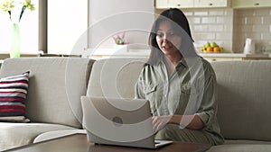 Smiling young indian woman video calling using laptop webcam conference at home.