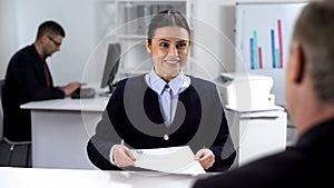 Smiling young job applicant giving curriculum vitae to hr manager, interview