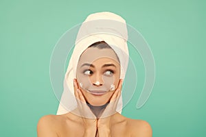 smiling young lady applying face cream on blue background