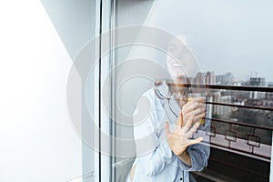 Smiling young lady standing at home looking at window