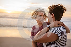 Smiling young lesbian couple watching a beach sunset together