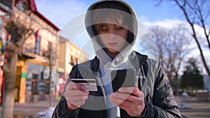 Smiling young male customer holding credit card and smartphone. Happy men shoppers using instant simple mobile payments