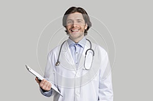 Smiling young male doctor in white coat with stethoscope and clipboard