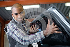 Smiling young male mechanic inspecting car in auto repair