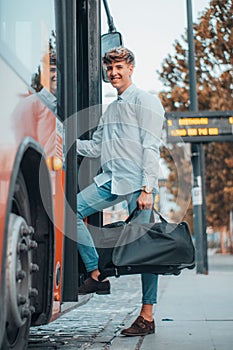 Smiling young male Spanish carrying a black bag while riding up a bus