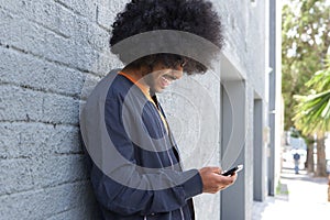 Smiling young man with afro using cell phone