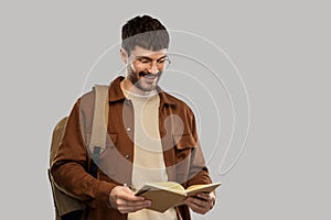 Smiling young man with backpack reading diary