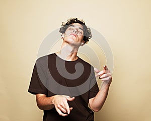 A smiling young man in a brown t-shirt dances on a beige studio background, enjoys life