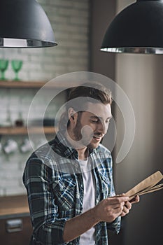 Smiling young man carefully reading old papers