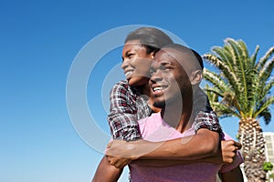 Smiling young man carrying girlfriend on back