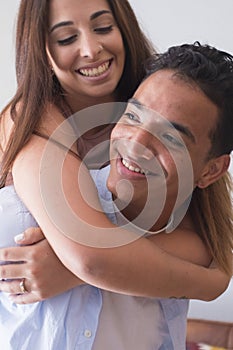 Smiling young man carrying woman on his back and laughing at home - young couple people in piggyback have fun together enjoying