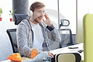 Smiling young man in casual clothing using computer, streaming playthrough or walkthrough video