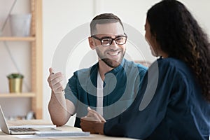 Smiling young man chatting with mixed race female colleague.