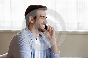 Smiling young man chatting on phone, having pleasant conversation