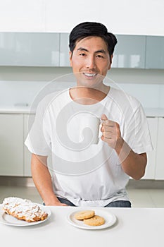 Smiling young man drinking coffee in kitchen