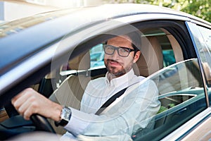 Smiling young man driving his car through the city streets