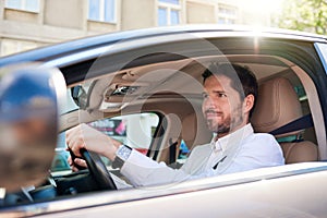 Smiling young man driving his car during his morning commute photo