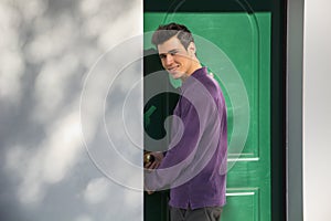 Smiling young man entering a door