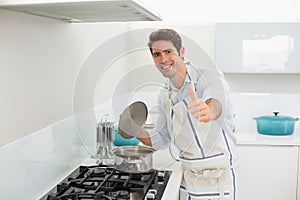 Smiling young man gesturing thumbs up in kitchen