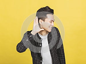 smiling young man hand over ear listening an hearing to rumor or gossip
