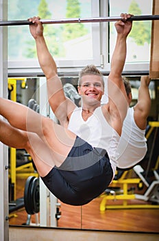 Smiling young man hanging from gym equipment