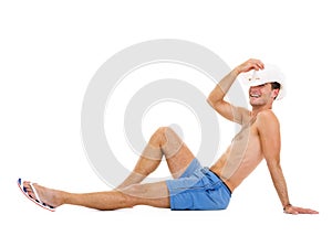 Smiling young man in hat sitting and tanning