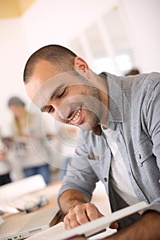 Smiling young man having fun reading book